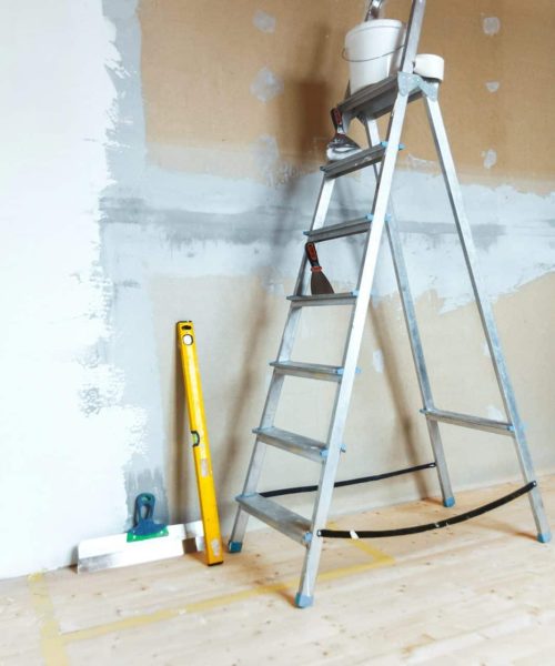 A stepladder with painting tools in a room. Preparing for putty